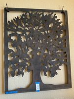 Front view of a large metal wall hanging with a tree cutout design, rectangular frame, dark metal finish.