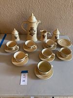 Full view of Pfaltzgraff Village coffee set displayed on a table showing cups, saucers, coffee pot, sugar bowls, and creamer.