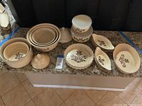 Full view of all Pfaltzgraff Village ceramic cookware pieces displayed on counter, showing all items in collection including lids and various bowl sizes.
