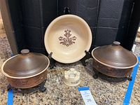 Front view of Pfaltzgraff Village servingware set showing 12-inch serving bowl on stand, two copper-tone warmers with lids, 9.25-inch dish, and sauce warmer