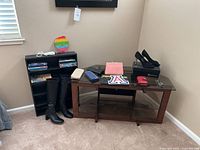 Overview of all items together: framed art on wall, boots on floor, wallets and shoes on table, DVDs in shelves.