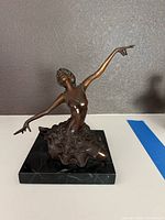 Front view of bronze ballerina sculpture on marble base showing posture and detail of arms and tutu.
