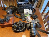 Overview of DSLR, lens, camera bags, binoculars and accessories on table