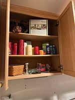 Open cabinet with floral arrangement, candles, laundry detergents and cleaning products