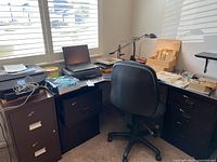 Full view of office desk setup with Lenovo laptop, filing cabinets, chair, lamp, and various office supplies by window
