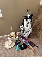 Full view of golf bag, hats, and umbrellas bundle showing all included items.
