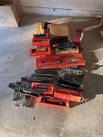 Overview of Lionel trains, freight cars, box packaging, and assorted metal railroad tracks spread out on the floor.
