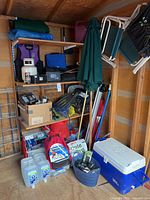 Photo of shelves storing multiple outdoor and camping items including cooler, chairs, umbrella, water containers, life vest, and storage boxes.