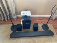 Soundbar, subwoofer, two surround speakers and two stands arranged on floor