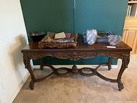 Full view of the antique vintage wooden side entry table with accessories on top