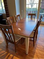 Photo showing rectangular wooden dining table with 7 chairs around it in a room setting near glass doors.