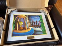 Framed print of Tweety Bird in a birdcage with urban backdrop inside protective packaging box.