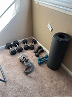 Overview photo of weights workout bundle showing pairs of dumbbells, yoga mat, and brace arranged on carpet.