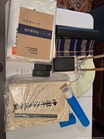 Photo showing multiple calligraphy brushes, ink stones, folded fan, papers, and reference books arranged on a table for calligraphy practice.