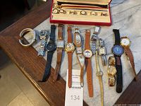 Photo showing full assortment of about 12 wristwatches with varied straps and styles. Includes gold-tone Wittnauer near center.