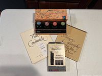 The Writing Collection ink set with four bottles of ink, Speedball calligraphy pen in packaging, and two pads of calligraphy paper.