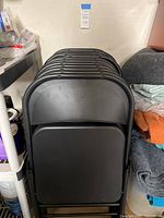 Stack of black metal folding chairs showing curved backrests and flat seats