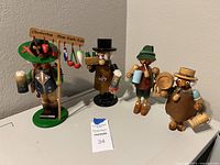 All four wooden smokers displayed together showing different beer-themed accessories and colorful attire.