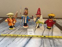 Full front view of four roly poly wooden smokers dispersed in a line showing different characters and their props.