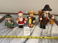 Four Steinbeck roly poly smoker figurines set on a table with measuring tape showing approximately 4 to 8 inch sizes.