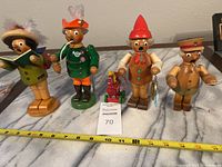 Four wooden smokers lined up on a marble surface with a measuring tape showing size around 6-7 inches tall