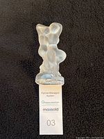 Photo of Lalique frosted glass figurine sculpture La Faune (Pan & Diane) from front view on black background with auction ticket.