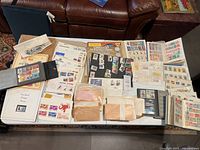 Top-down view showing a large collection of loose and album-contained stamps spread over a table including envelopes and small albums.