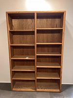 Front view of a large oak veneer bookcase with 8 shelves divided into two equal halves for storage.