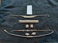 Overview of six pieces on black background: top Weiss necklace, bracelet, square earrings, unmarked necklace and earrings, Anne Klein necklace