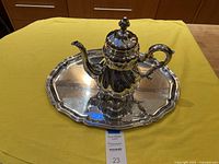 Overall view of teapot placed on matching tray atop yellow cloth background