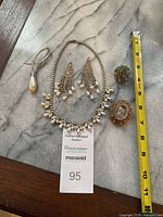 Overview of all five jewelry pieces laid out: pearl drop pin, necklace, earrings, blue stone brooch, cameo brooch