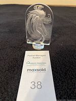 Front view of the clear crystal figurine on a black background with an auction number card.