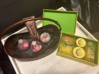 Photo showing dark brown brass basket containing three pump bottles with pink labels plus one pink foil-wrapped bath product