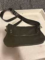 Full view of the black leather crossbody bag showing the adjustable strap and main compartment.