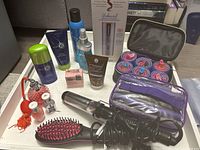 Full view of beauty and hair styling products showing hair care products, nail polishes, perfume atomizer, hair rollers, curling iron, and hairbrush.