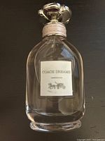 Front view of Coach Dreams Eau de Parfum 60ml bottle showing label and floral silver cap.