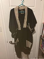 Black Tara Vao linen dress with beige linen accented shrug hanging on hanger.