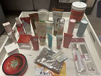 Overview of all skincare products in the lot placed on a white tray, showing a variety of brands and packaging types including tubs, tubes, and boxes.