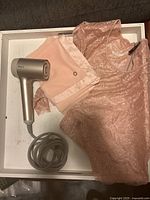 Pink lace Guess shirt, pink Calvin Klein scarf, and Shark HyperAIR hair dryer arranged inside a tray.