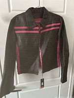 Front view of black leather jacket with pink stripes hanging on a hanger showing collar, sleeves and zipper front.
