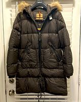 Full front view of brown puffer jacket with zip and snap closure, front pockets, fur-trimmed hood