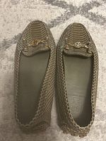 Top-down view of olive faux snakeskin leather loafer pair showing gold-tone Tory Burch logo chain embellishment on vamp