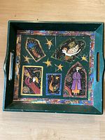 Square wooden plate with Marc Chagall style painted motifs including birds, stars, and a person, showing the entire plate with handles on each side.