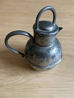Small antique pewter pitcher with rounded body, handle, spout and lid with looped handle