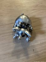 Front angled view of the silver pig figurine on wooden surface showing body and facial features.