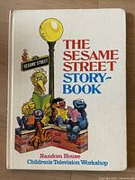 Front cover of vintage Sesame Street children's book titled 'The Sesame Street Story Book' showing characters Big Bird, Grover, Cookie Monster, Ernie, Bert, and Oscar reading books.