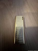 Top view of lighter showing engraved geometric pattern on gold-tone metal body.