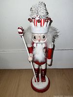 Front view of the large peppermint-themed nutcracker showing the full figure, hat, beard, and staff.