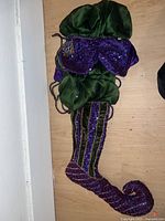 Front view of large purple and green silk Christmas stocking with curled toe and decorative beading.