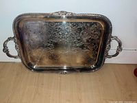 Front view of the large silver tray showing detailed floral etchings, ornate handles, and decorative border.